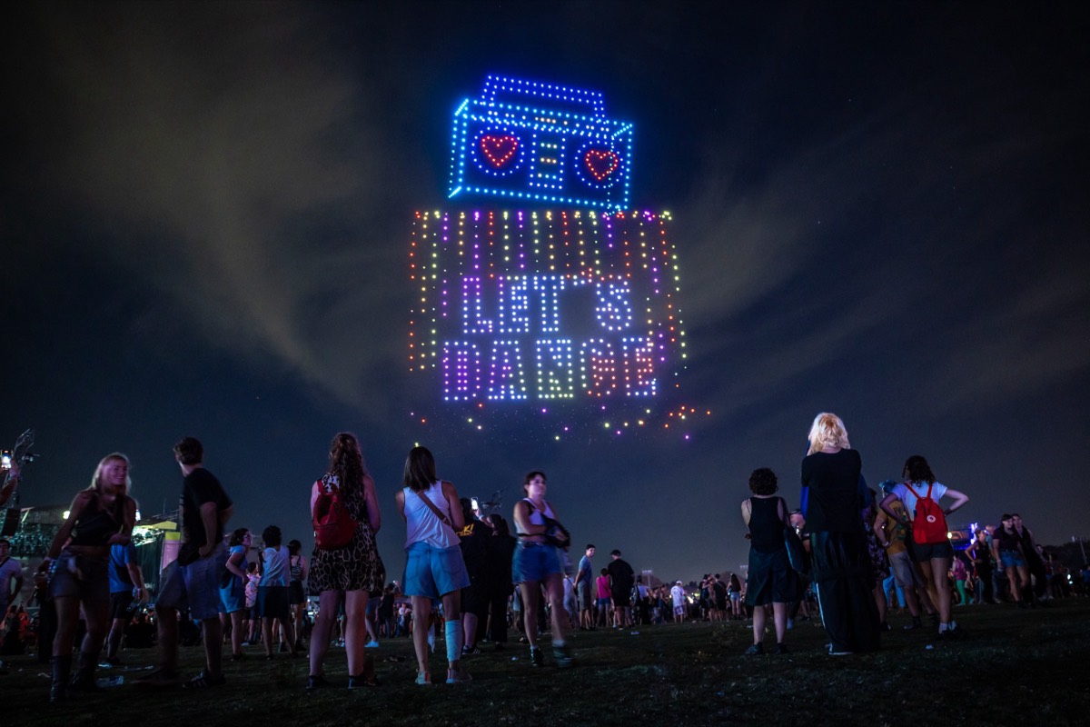 Radio et message « Let's dance » dessinés par des drones au-dessus du public d'un festival