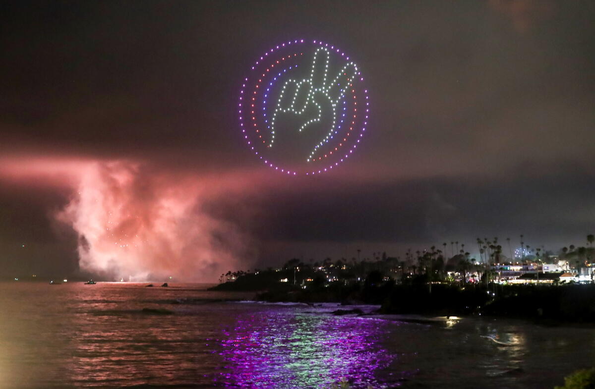 Main faisant le signe de la paix dessinée par des drones au-dessus d'une ville en bord de mer